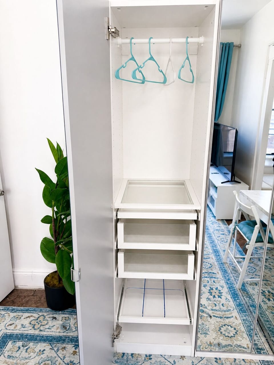 Bright, organized wardrobe with hangers, pull-out drawers, and mirror
