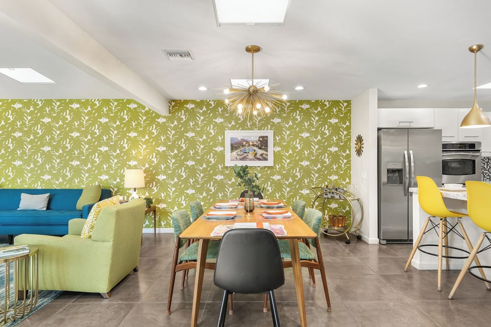 Dining area with black chairs and green accent wall.