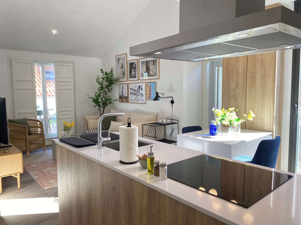 View of a modern kitchen island and a bright living area beyond.