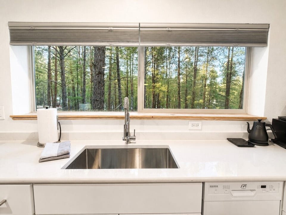 A deep sink and forest-view window bring light and calm into the kitchen.