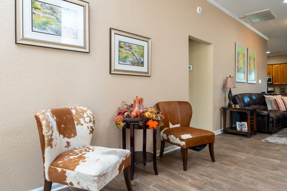Warm living room with plush seating, rustic stone fireplace, hardwood floors, free Wi-Fi, and central AC & heat