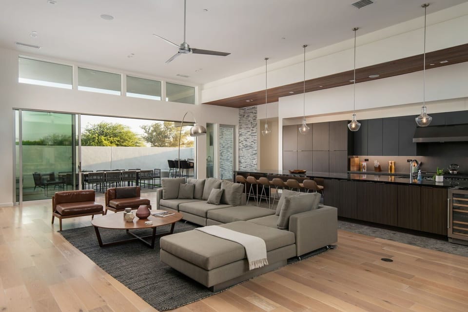 The stunning open-concept design connects the gourmet chef's kitchen, featuring a black marble island and warm wood ceilings, to the comfortable living area.