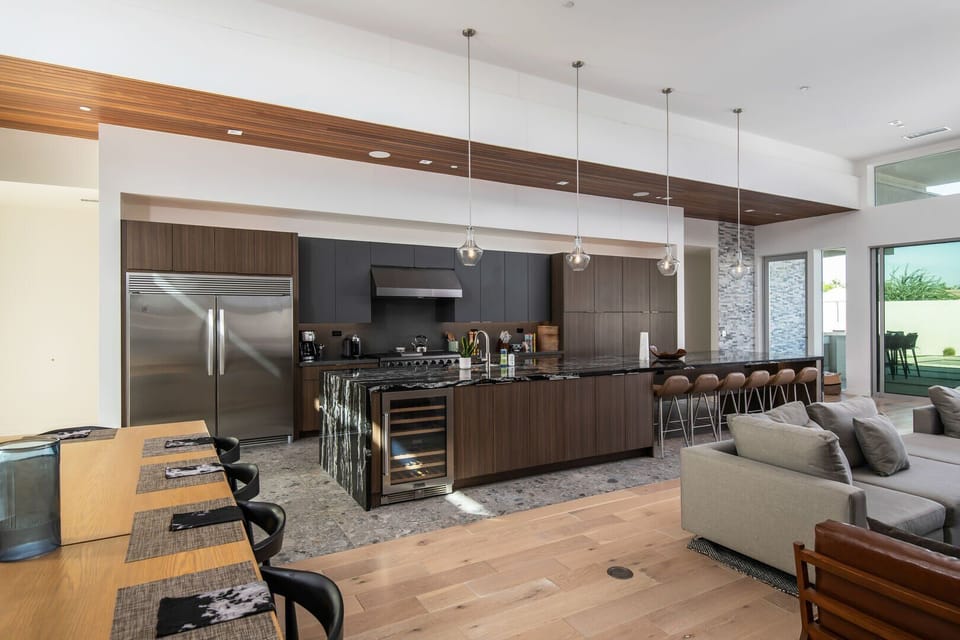 The gourmet chef's kitchen, anchored by a massive waterfall marble island with counter seating and a built-in wine fridge.