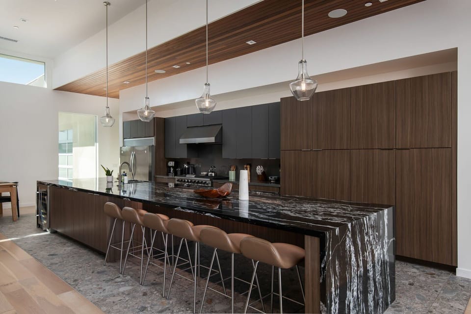 The gourmet chef's kitchen, anchored by a massive waterfall marble island with counter seating and a built-in wine fridge.