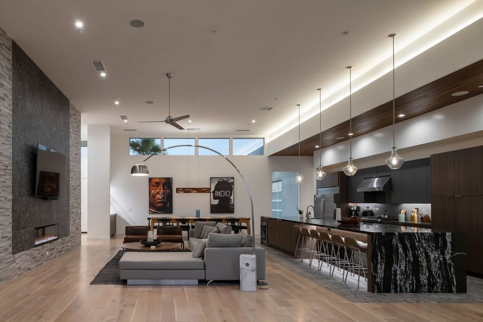 The spacious, open-concept great room at night, perfectly blending the high-end kitchen, lounge, and dining areas.