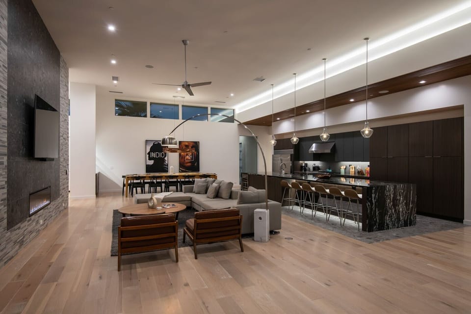 The stunning open-concept great room at night, showcasing the living area, dining space, and gourmet kitchen with high ceilings and custom lighting.