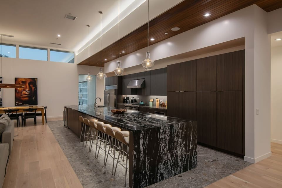 A close-up of the gourmet chef's kitchen, highlighting the massive marble island, custom cabinetry, and sophisticated lighting.