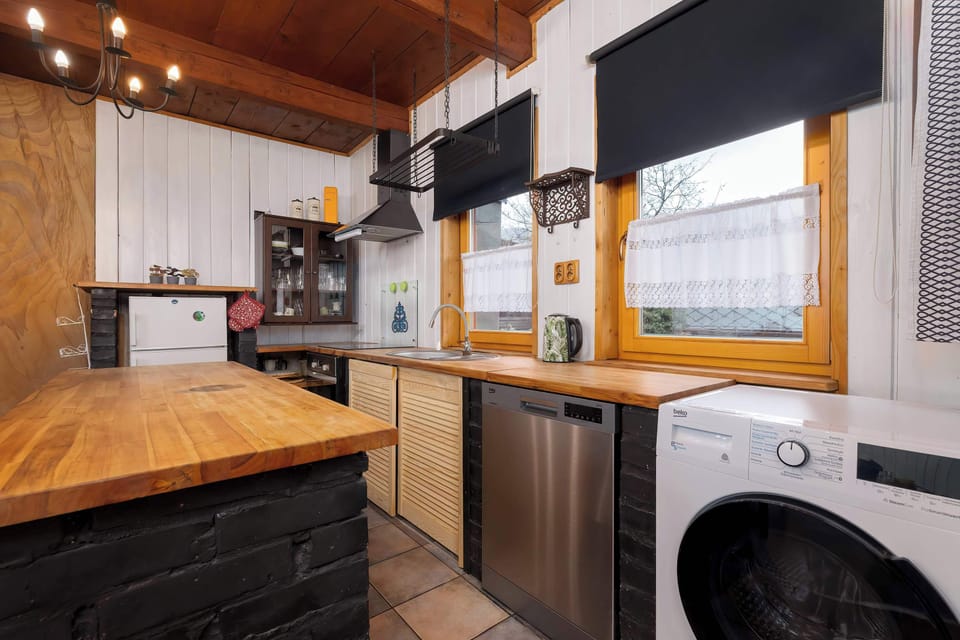 Another angle of the same kitchen showing a gas stove, washing machine, and plenty of workspace. Warm lighting enhances the cozy atmosphere.