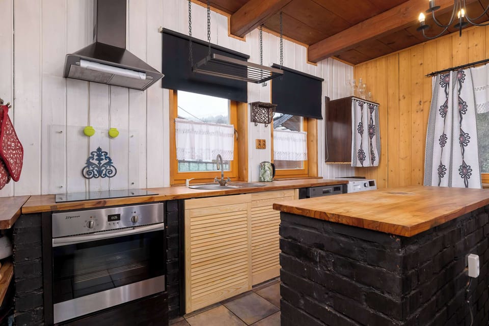 A modern kitchen with wooden countertops, white cabinets, and black accents. The layout is functional and stylish, matching the overall rustic theme.