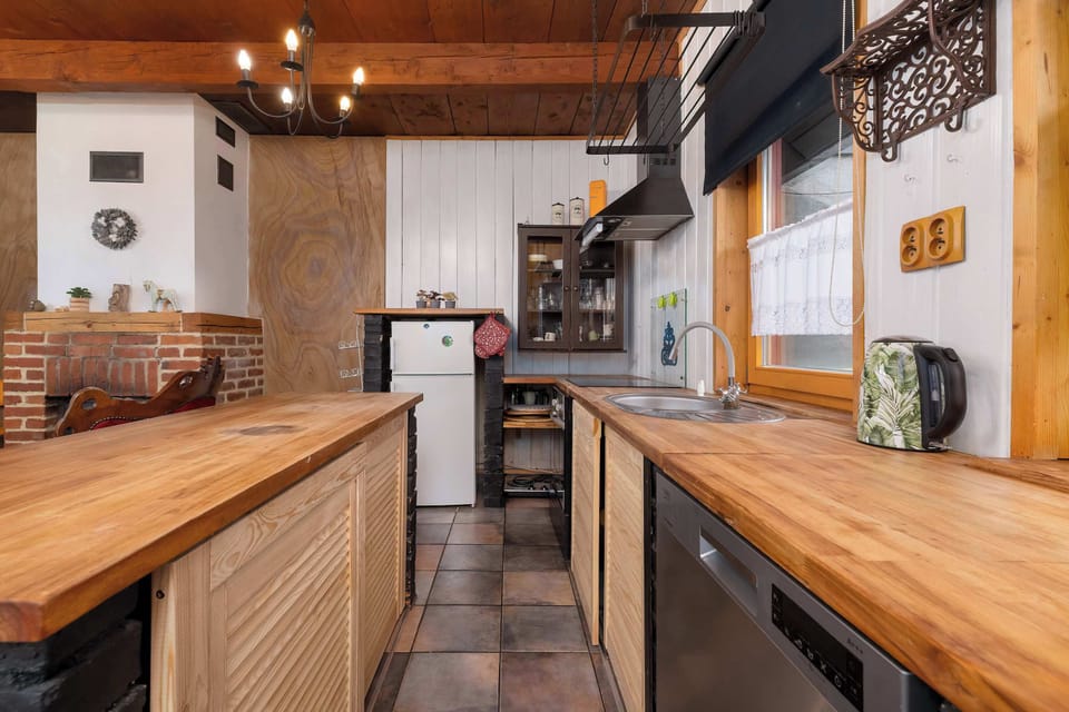 A small kitchen space with a rustic sink and wooden shelves. The combination of textures gives it an old-world charm.