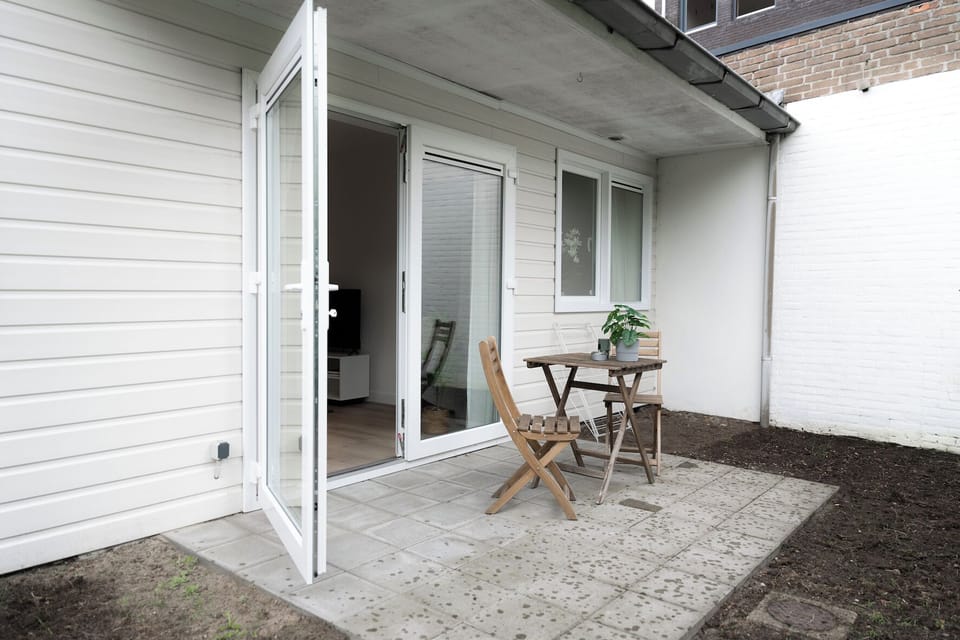 Private terrace with open garden access, featuring a cozy bistro set — perfect for morning coffee or relaxed outdoor evenings.