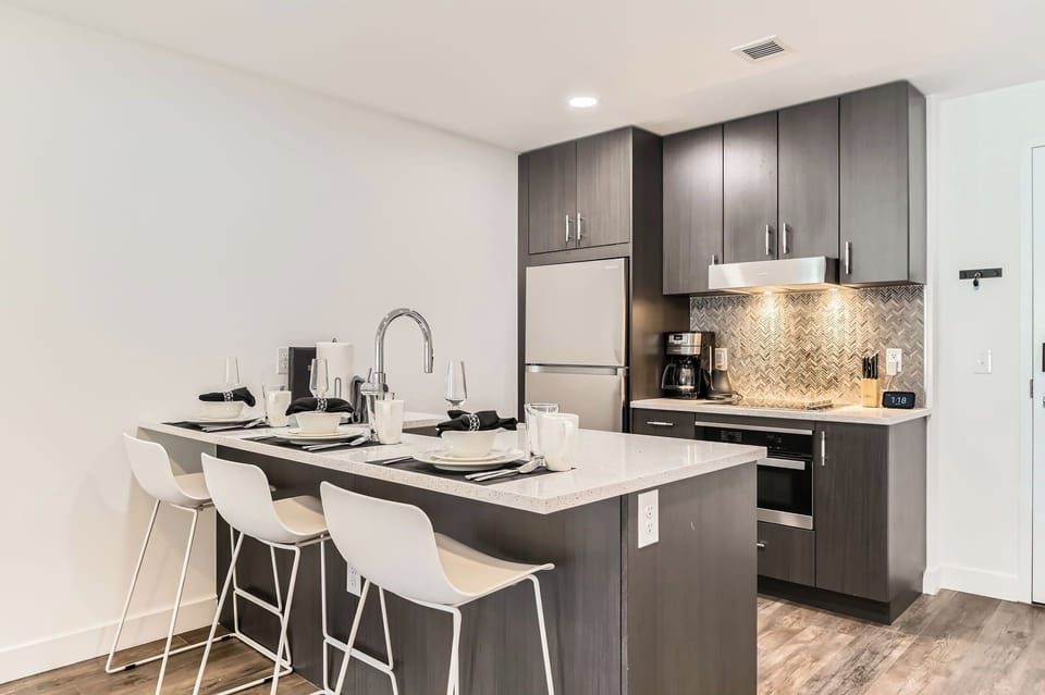 Enjoy this fully equipped kitchen featuring sleek quartz countertops and a spacious island with modern seating. Prepare meals with ease using the stainless steel appliances during your stay.