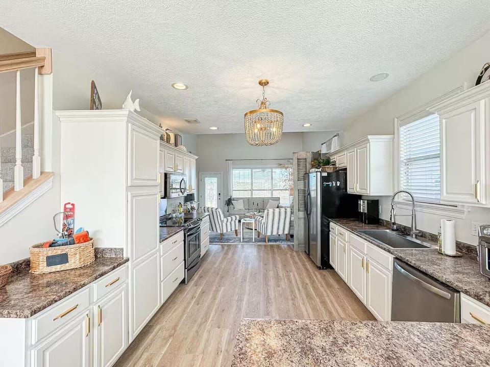 Spacious, sunlit kitchen featuring ample counter space, stainless steel appliances, and stylish lighting, perfect for cooking and entertaining.