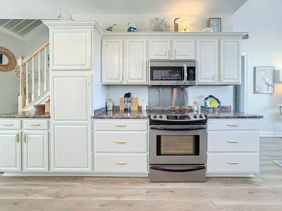 Spacious, sunlit kitchen featuring ample counter space, stainless steel appliances, and stylish lighting, perfect for cooking and entertaining.
