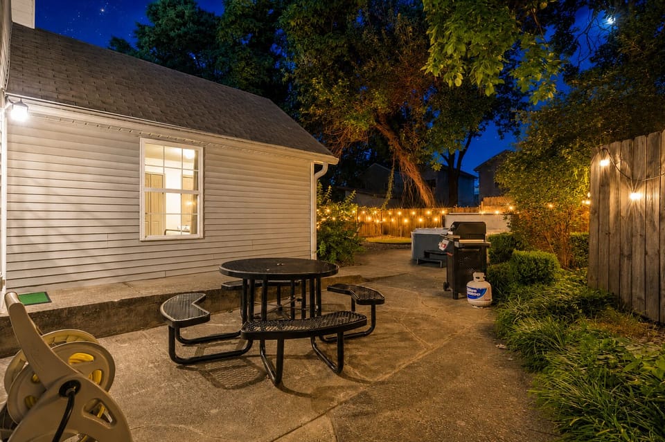 Cozy lit patio with hot tub, grill, and outdoor dining space