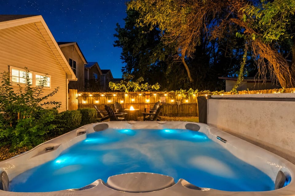 Private hot tub oasis with fire pit seating and cozy string lights