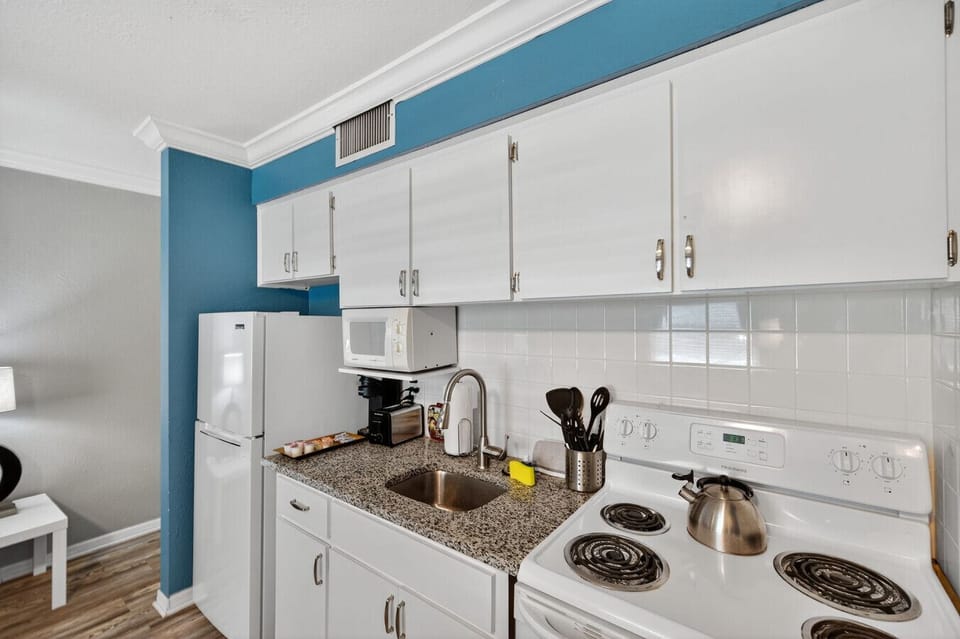 Bright kitchen view showcasing sleek counters, white cabinets & a functional layout.
