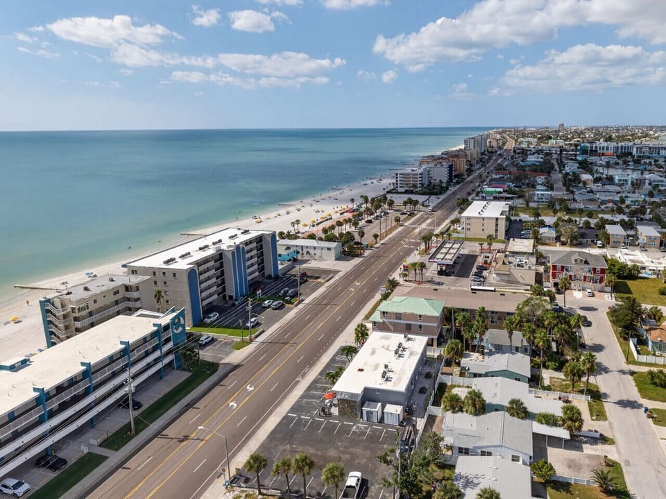 Long shoreline view capturing the coast, roadways & nearby buildings.