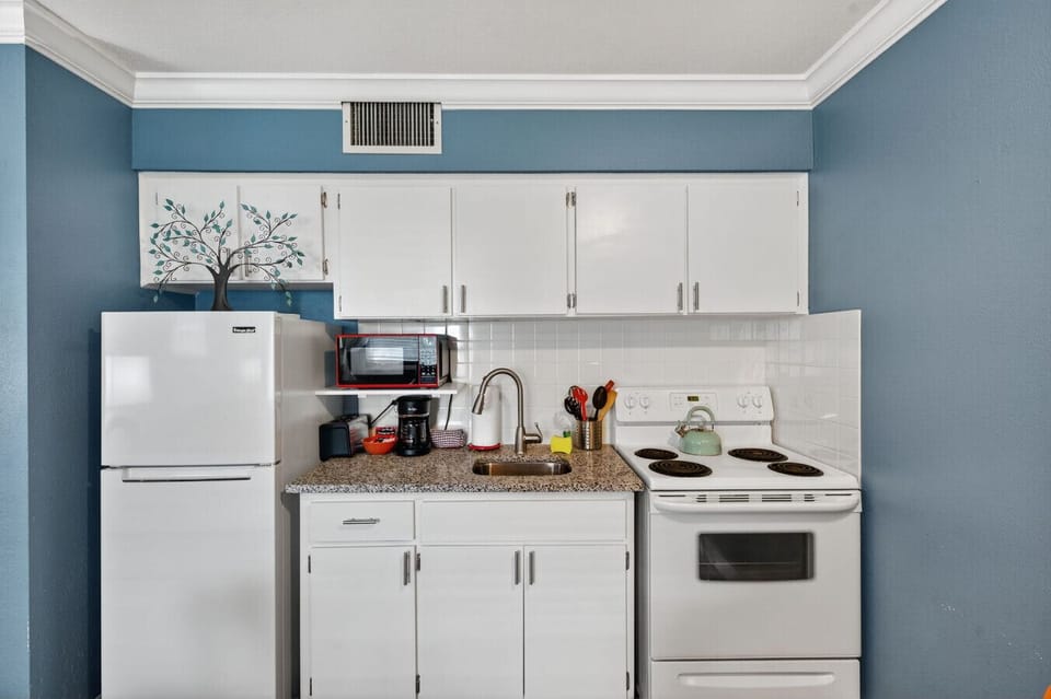 Clean, compact kitchen w/ white cabinets & everything set up for simple meals at home.