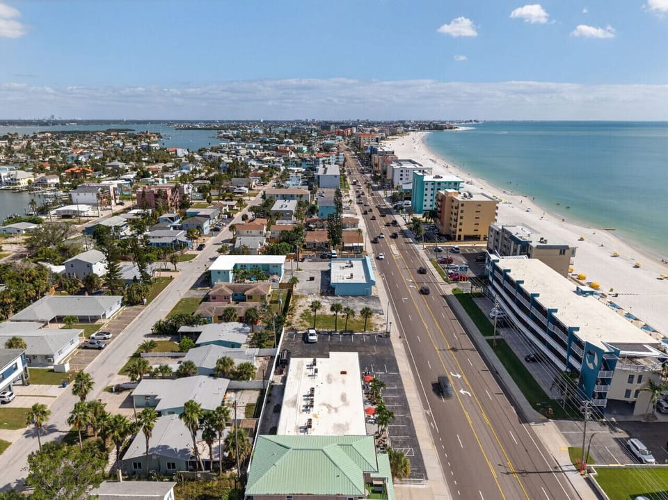 Bird’s-eye view capturing the shoreline, nearby buildings, & sparkling water.