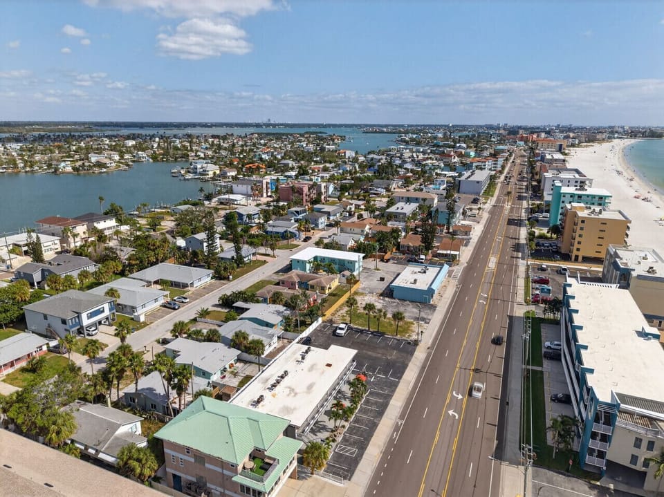 Elevated shot along the main road, capturing buildings, traffic flow, and nearby water.