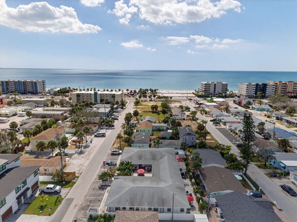 Wide aerial perspective w/ the Gulf visible beyond the surrounding neighborhood.