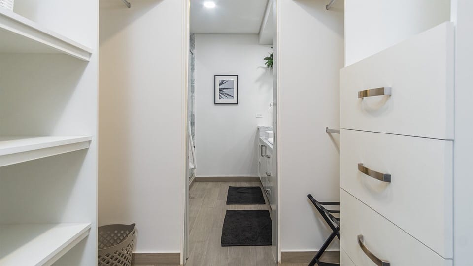 Walk in closet of the first bedroom leading to the bathroom.