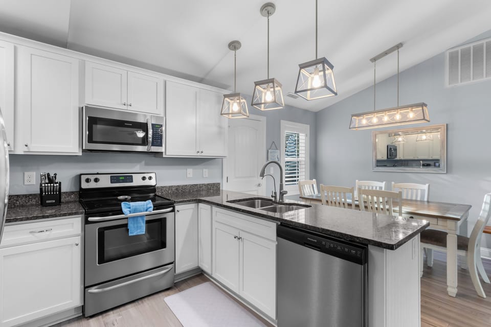 Chef‑ready kitchen featuring stainless steel appliances, granite countertops, a large island with extra seating, and every cooking essential