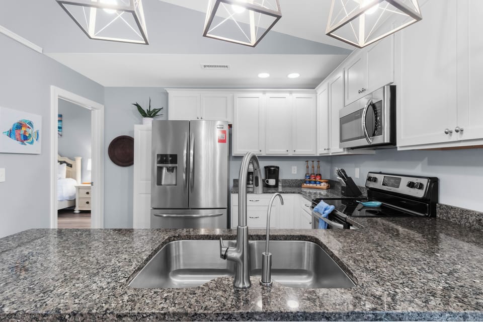 Chef‑ready kitchen featuring stainless steel appliances, granite countertops, a large island with extra seating, and every cooking essential
