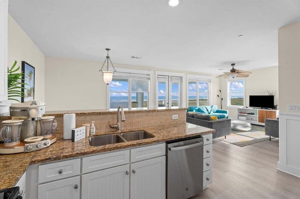 Open kitchen and living area featuring granite countertops, abundant natural light, and beautiful views from multiple windows.