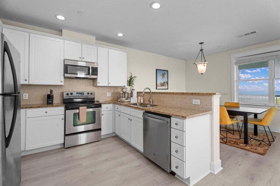 Fully equipped kitchen with stainless steel appliances, granite countertops, ample cabinetry, and spacious meal preparation areas.