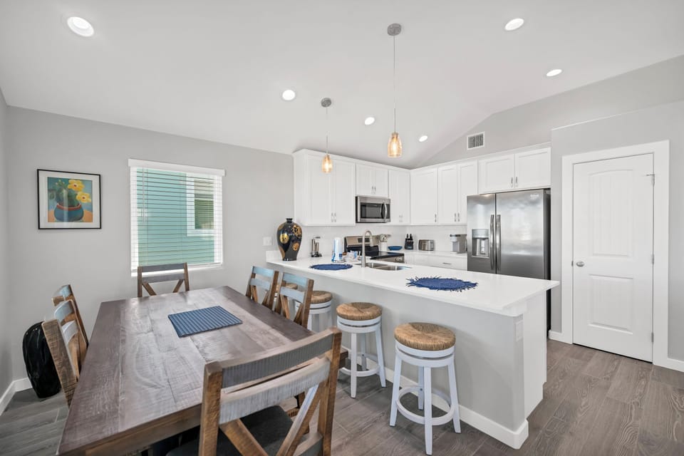 Your bright kitchen-dining space features modern white cabinetry, stainless steel appliances, and a breakfast bar perfect for morning coffee or evening meals together.