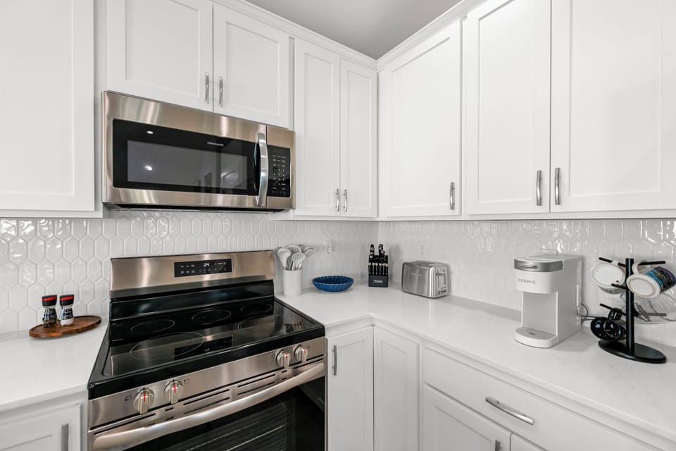 Your fully equipped kitchen awaits with gleaming stainless steel appliances and pristine white cabinetry, perfect for preparing memorable meals during your stay.