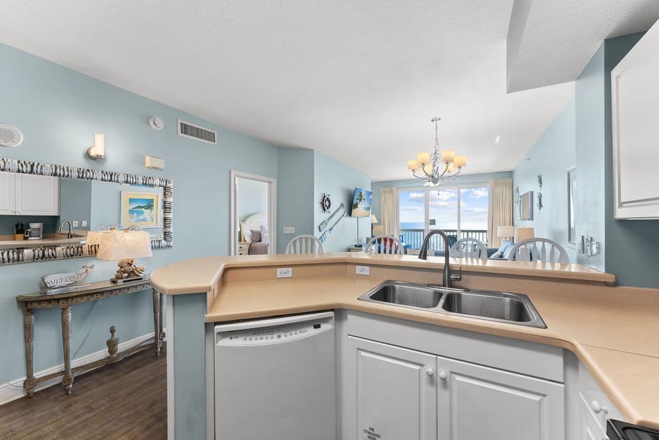 Open kitchen w/ bar seating, sink, & a clear sightline to the dining area beyond.
