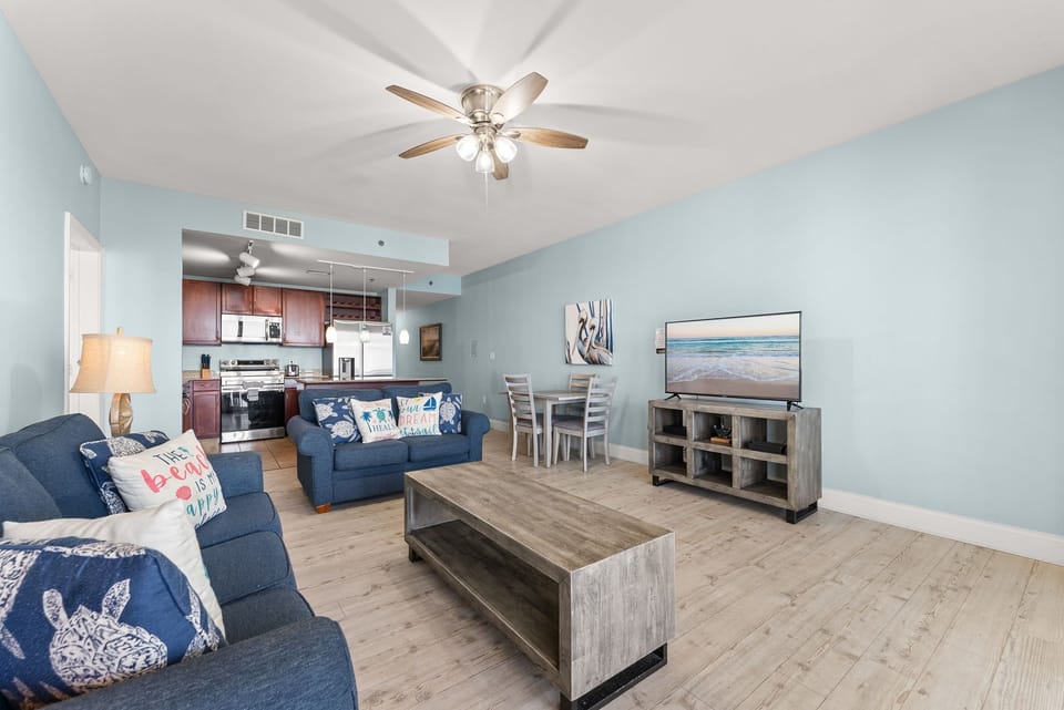 Spacious living area with coastal-inspired decor and an open kitchen layout.