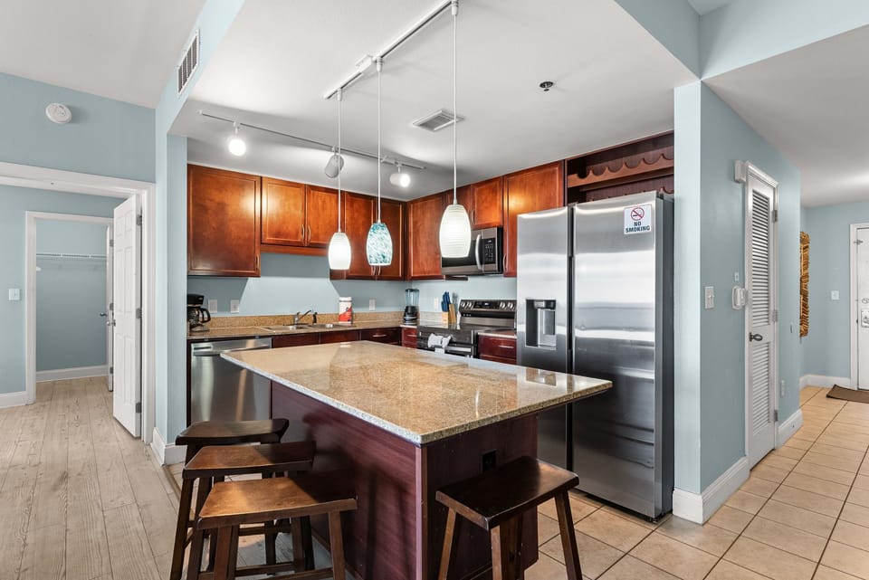 Modern kitchen with stainless steel appliances and a spacious granite island for dining and meal preparation.