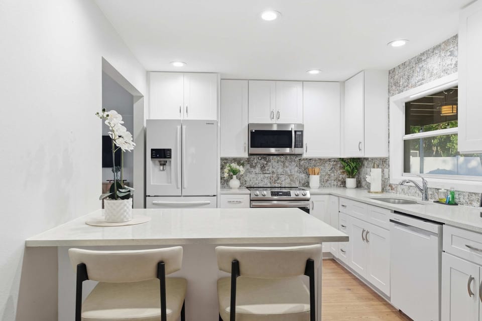 Bright, modern kitchen with white cabinetry, sleek stainless appliances, and a cozy breakfast bar. Perfect for morning coffee or evening meals, this space combines elegance and function for a seamless guest experience.