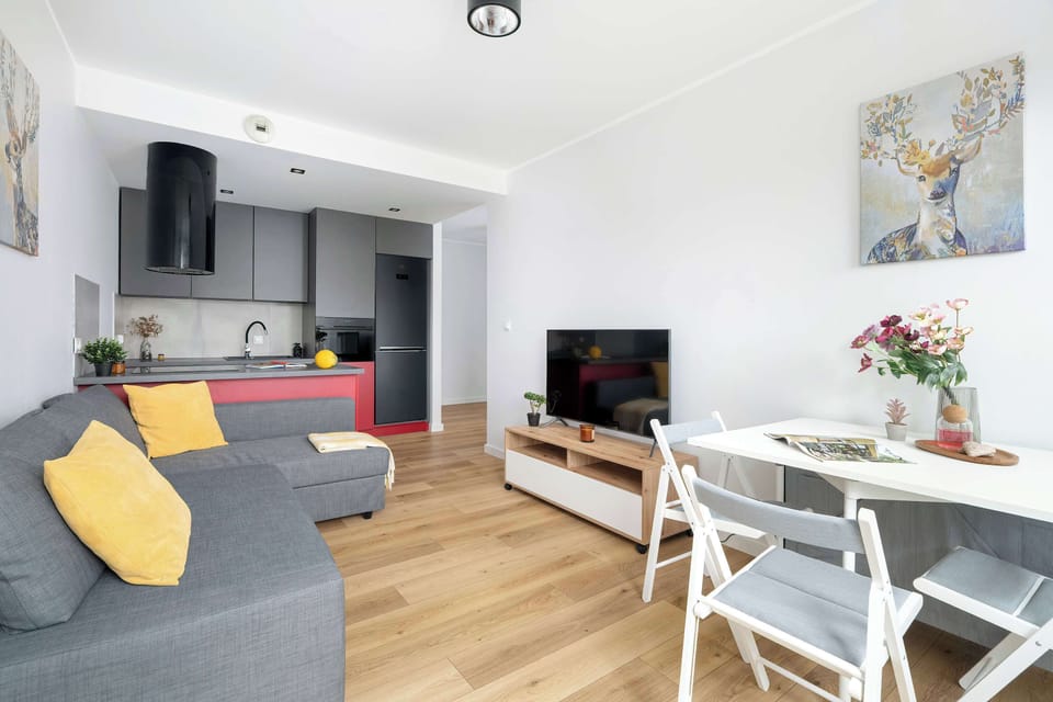 The living area features a sleek dining table and a flat-screen television.