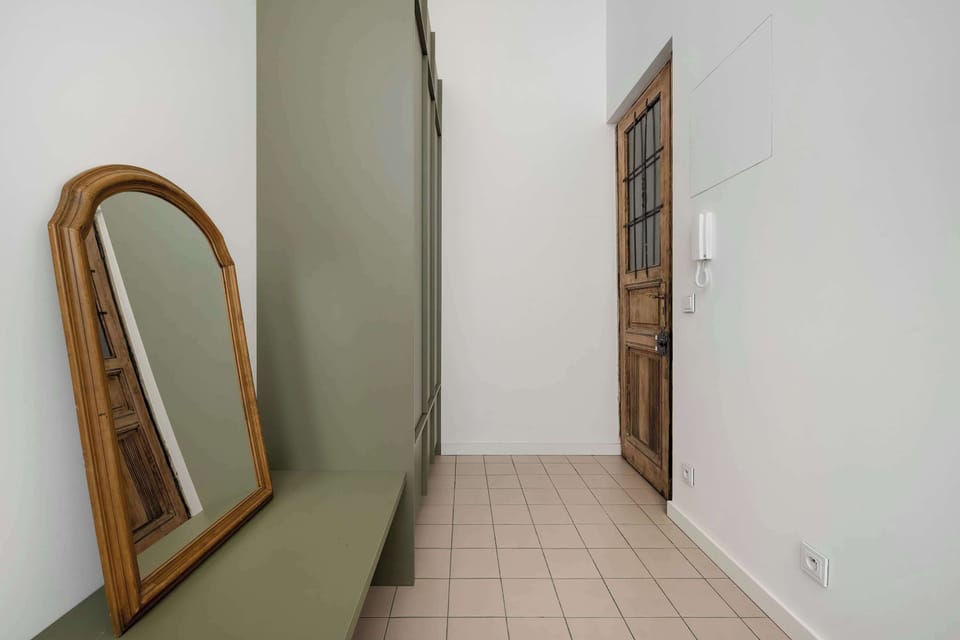 A hallway corner with a green bench and large mirror. The space is clean, practical, and thoughtfully styled.