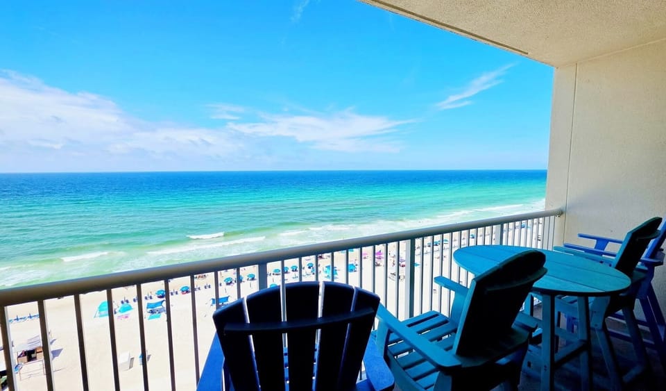 Beach side view of the Gulf from balcony with 4 pub chairs and table.