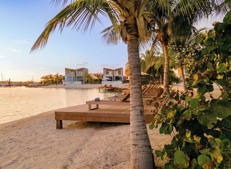 Stretch out under swaying palms with calm water at dusk.
