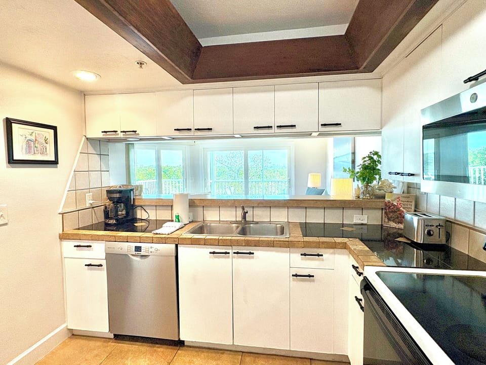 Kitchen with white cabinets, stainless steel sink, coffee maker, and natural light from window