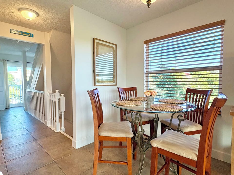 Dining area with table and chairs and sliding glass door with pool and water views beyond