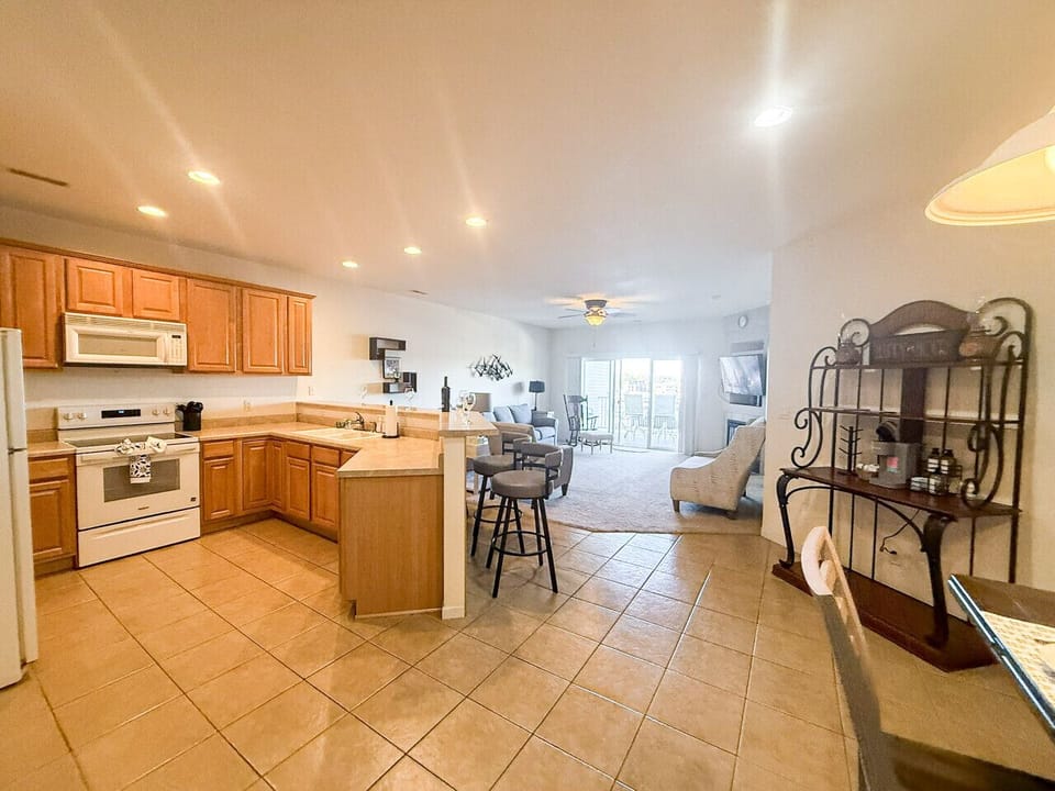 Modern open-concept kitchen and living space with breakfast bar, full appliances, and balcony access