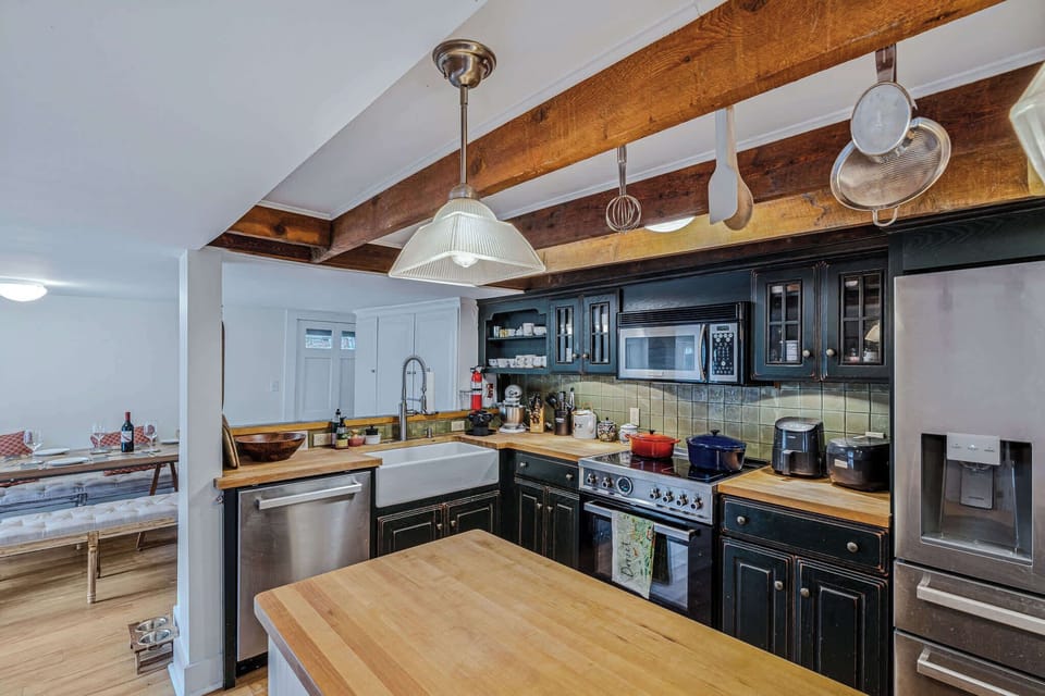 Farmhouse kitchen with butcher block counters, exposed beams, and pot rack