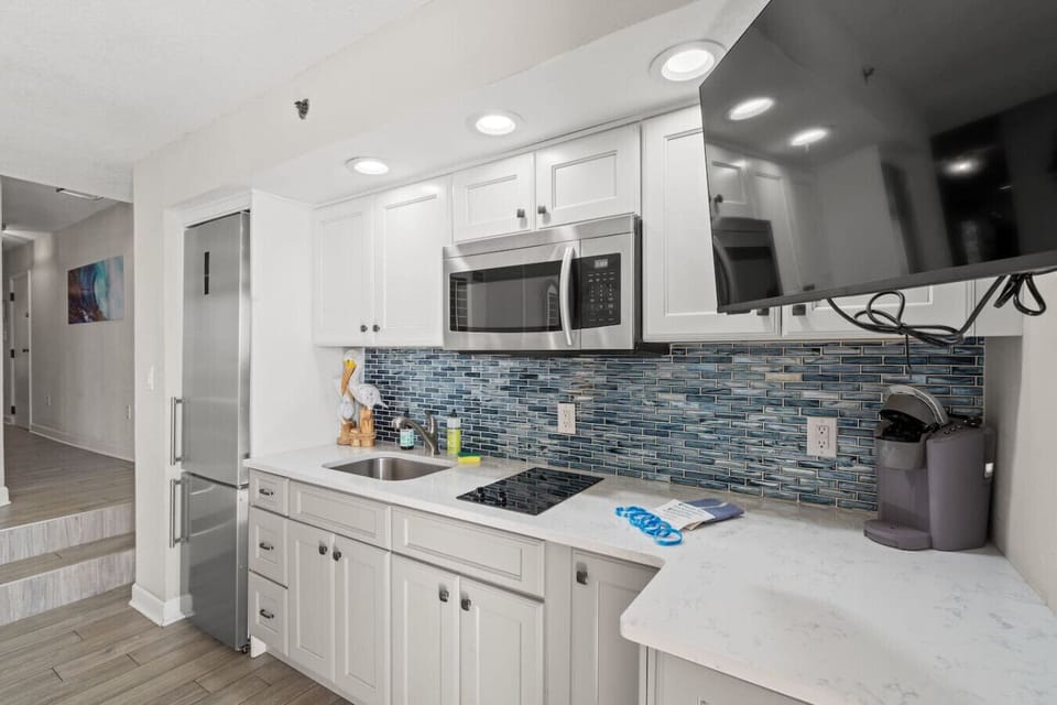 This gorgeous oceanfront living room adds energy to the day with floor to ceiling lighting. Large modern stainless steel refrigerator counter top 2-burner stovetop, Smart tv, microwave, Keurig coffee maker, dinnerware, cookware, ands silverware.