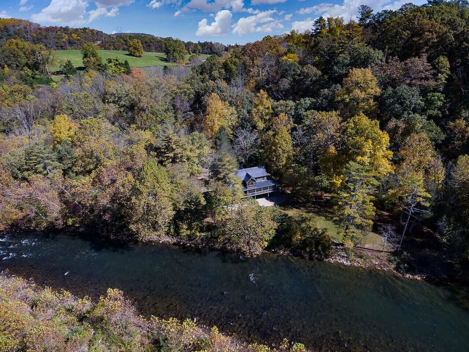Stunning Aerial View of the Property Nestled Among Lush Green Trees with a Scenic River Beside It