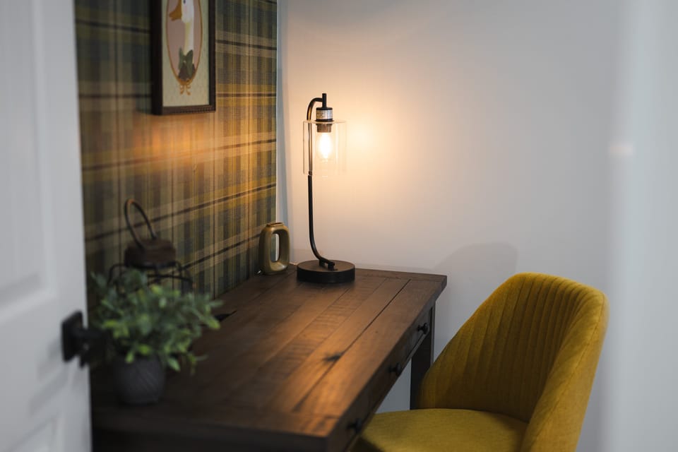 Bright twin bedroom with desk and chair, cozy corner chair, and a toy shelf with toys for children.