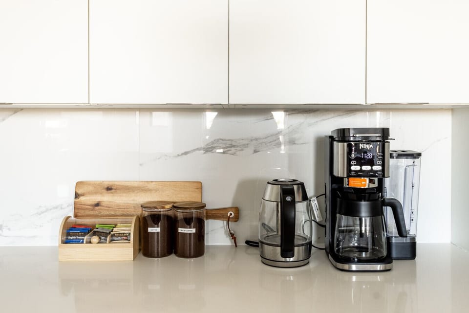 Kitchen with oven, microwave, fridge, dish washer, coffee maker, tea kettle, tea, coffee, mixer, mixing bowls, kitchen utensils, toaster