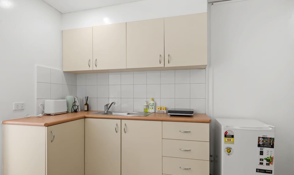 Compact and practical kitchenette with storage cabinets and essential appliances.